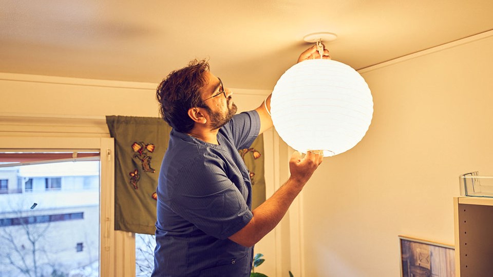 En man sätter upp en lampa i en lägenhet