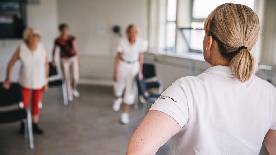 Äldre kvinnor som tränar i en gymnastiksal med en instruktör