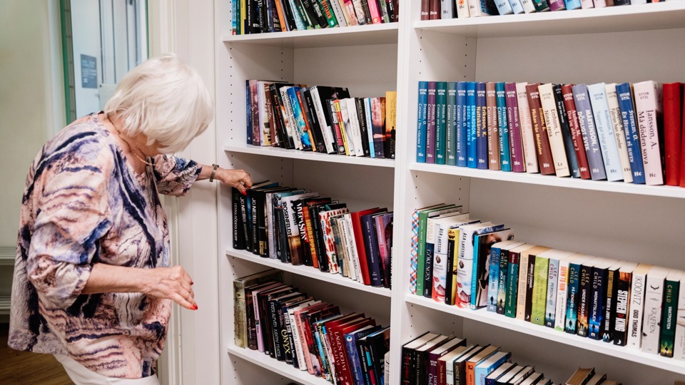 Äldre kvinnor som letar bok i ett bibliotek