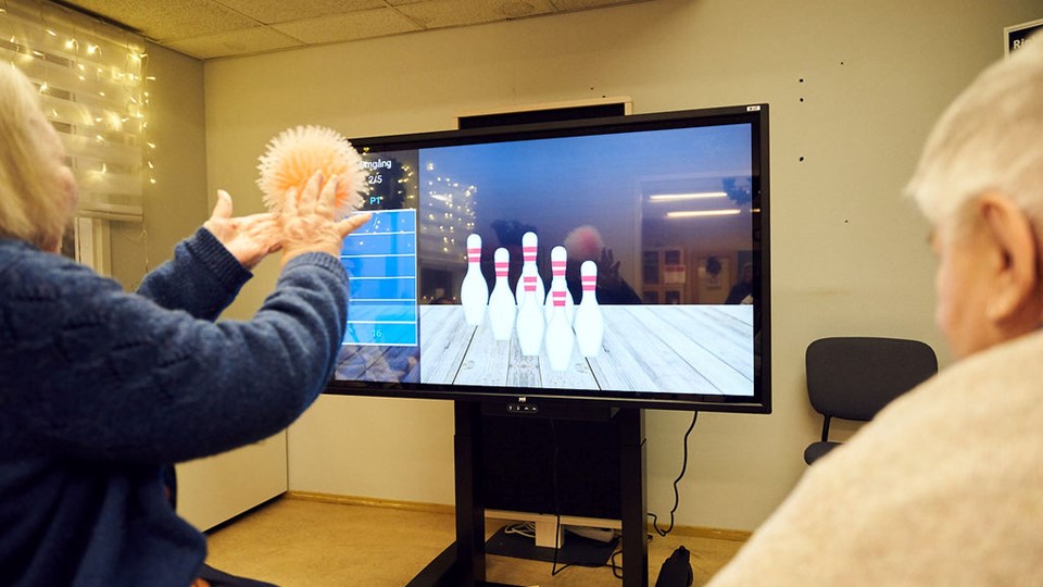 Seniorer spelar ett bowlingspel på en teve-skärm
