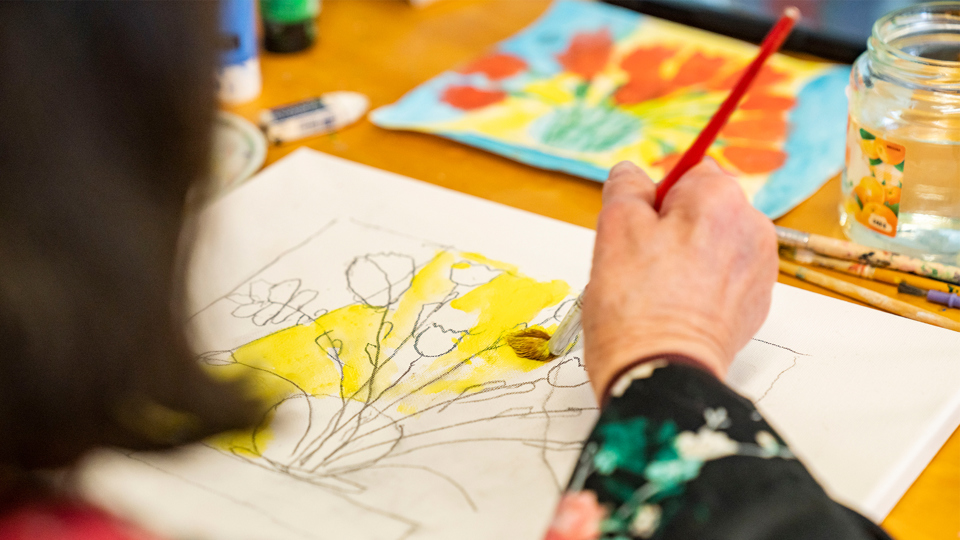 En person tappar upp kaffe i en mugg vid en kaffemaskin, med mat och dryck på brickan bredvid.