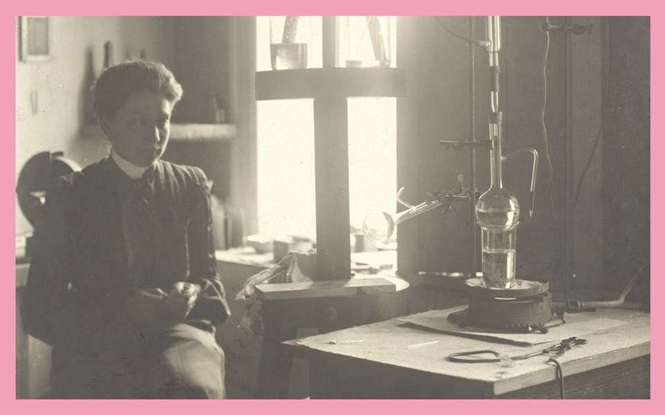 Kvinna sitter i laboratoriemiljö tidigt 1900-tal. Foto.